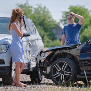 A couple stands next to a car with visible damage, symbolizing ''car accident'' - Brian Moore Injury Law